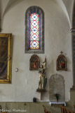 <center>Barrême </center> L’église Saint-Jean-Baptiste <br>  Statue (grandeur nature) : La Bienheureuse Jeanne d'Arc. Les verrières décoratives sont composées de cinq quadrilobes superposés, contenant une fleur, dans un encadrement alternant médaillons circulaires ou carrés et feuilles stylisées, aux couleurs rouge, vert ou jaune.