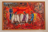 <center>Abraham et les trois anges</center>1960-1966.
Huile sur toile.
Trois anges, messagers divins, viennent annoncer à Abraham et Sarah, alors très âgés, la naissance prochaine d'un fils. Chagall met en avant les trois anges à qui Abraham offre l'hospitalité. La composition est marquée par l'horizontale du banc au premier plan et rythmée par un jeu de verticales. La couleur dominante du tableau est le rouge, couleur de la vie et de l'amour, mais aussi celle du fond des icônes dont l'or, usé, laisse apparaître une couche de rouge. Par contraste, la blancheur des ailes des trois anges apparaît éclatante et rappelle l'icône de la Trinité d'Andrei’Roublev (Galerie Tretyakov, Moscou). En haut à droite, Chagall représente la suite du récit : Abraham reconduit les trois anges qui, sur ordre divin, vont détruire les villes de Sodome et Gomorrhe.