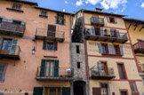 <center>Péone</center>La place de la Mairie. Le village est bien groupé en rond. Ses hautes maisons à colombages sont à la fois de type alpin et italien : encadrements des portes et fenêtres, balcons à fers forgés en saillie, toits en bardeaux ; à l'étage supérieur, auvents-granges.