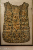 <center>Cathédrale Notre-Dame de la Nativité</center>CHASUBLE baroque
Fin XVIe ou début XVIIe siècle.
Origine et datation cette chasuble ne provient pas de l’évêché de Vence, elle nous a été offerte par une donatrice qui l'a trouvée dans la cave de ses parents à Nice. Elle pourrait provenir d'Italie ou d'Espagne. Par son décor baroque, on peut la dater de la fin du XVIe ou du début du XVIIe siècle (étude en cours). Le concile de Trente, convoqué en 1580 par le pape Paul III Farnèse (notre ancien évêque) encouragea cette expression baroque de surcharge décorative et d'exubérance qui servait la propagande catholique de la Contre-Réforme
Tissus : soie bleue, doublée de toile beige
Décor : il recouvre la totalité des pans ; celui de devant, de forme violon très prononcée, est décoré d’un vase à deux anses d'où s’élève une branche à deux grosses fleurs entourée de deux petits bouquets se détachant sur un fond entièrement brodé ; sur l’arrière, même type de décor mais la branche est entourée de cinq registre garnis de fleurs ou bouquets.