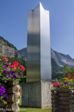 <center>Église Notre-Dame-de-Toute Grâce </center>Route de la sculpture contemporaine. Plaidoyer pour les droits de l'homme, 2000, Gilles Roussi. Cette haute tour à base carrée est en tôles d’acier inox. L’intégralité du texte de la Déclaration des droits de l’Homme est gravée sur ses quatre faces. Son sommet dessine un chaos qui traduit, à l’aide de la série trigonométrique du mathématicien Joseph Fourier, les “accidents” de l’histoire de France. Sa base, fichée dans un socle de béton, image par son relief les événements tragiques de notre monde depuis la Révolution française. Par cette oeuvre, Roussi (1947) met en jeu les valeurs humaines, les matériaux modernes, les mathématiques et la technologie de pointe.