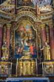<center>Saint-Nicolas-de-Véroce</center>Au centre, le tableau a été exécuté par Antoine Herzog, peintre actif à Vienne (Autriche), en 1733 représente un majestueux saint Nicolas, revêtu de ses insignes épiscopaux. Dans le ciel doré (et non bleu, façon de signaler que c'est le ciel de l'éternité, hors de l'espace et du temps) se tient la Trinité : Dieu le Père en bleu, le Fils Jésus en rouge, et l'Esprit sous la forme d'une colombe. La main du Christ indique la terre, trois anges, messagers de Dieu, font le lien entre Dieu et les hommes. Au centre, saint Nicolas, qui apaise la tempête, dote trois jeunes filles pauvres avec les boules d'or qu'un ange lui tend, et ressuscite les trois petits enfants du saloir du boucher.. La peinture est entourée des statues calmes et massives, de saint Roch et saint Etienne.