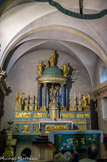 <center>L'église St-Michel </center>Il trouve place sous un dais formé de colonnes à chapiteau corinthien, couronnées d'un dôme à décor d'écailles. Le tabernacle reprend en réduction la composition de la partie haute du retable ; sur la porte est figurée l'Eglise.