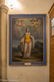 <center>Jouques.</center> Eglise Saint Pierre. Couronnement de sainte Consorce.  Peinture à l'huile, 19e siècle. Vierge et martyre, la sainte est représentée tenant dans la main droite le lys de la virginité. Elle est couronnée par un ange qui apporte également la palme du martyre. Invoquée contre la sécheresse, la sainte est représentée à l'arrière-plan portant un cruche d'eau sur la tête. Les noms des donateurs sont inscrits sur le cadre. Il s'agit des trois prieurs de la confrérie en fonction en 1850 : 1. Pierre Arbaud, 2. Etienne Michel, 3. Joseph Clément.
