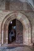 <center>Cathédrale Sainte-Eulalie-et-Sainte-Julie d'Elne</center>La porte par laquelle on passe de l'église au cloître est particulièrement riche. Son archivolte et ses piédroits, qui ont à une moulure près, un profil identique à celui de l'archivolte, comprennent des gorges et de larges bandeaux unis ou sur lesquels sont appliqués des tores. Les assises des piédroits et les voussoirs sont alternativement en marbre blanc et en marbre rouge. Les bases des colonnettes de la porte débordent leurs petits socles prismatiques et sont soutenues par des modillons. Les vantaux de la porte sont armés de pentures en fer forgé d'un style archaïsant datant du XIVe siècle.