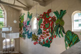 <center>Beauvoir-en-Royans</center>Couvent des Carmes. Claude Como. Révolutions, 2021.
Laine touffetée sur toile.
Depuis les années 1980, Claude Como (née en 1964, vit et travaille à Marseille) s’empare aussi bien de la peinture à l’huile, de la céramique, de la résine, du fusain ou encore de la laine pour sonder sa propre histoire et expérimenter son rapport aux réalités du monde, où le vivant trouve une place centrale. En 2019, Claude Como débute une série de tapisseries réalisée à l’aide d’un pistolet à tufter, traditionnellement utilisé par des artisans pour la réalisation de tapis, qui figurent des éléments végétaux foisonnants, des micro-organismes luxuriants, intitulée Supernature. Par leur souplesse, ces tapisseries s’extraient du cadre pour littéralement coloniser les murs et donner un caractère organique à l’architecture qui les abrite. Le choix du touffetage inscrit l’artiste dans une histoire de la tapisserie. En effet, depuis le Moyen Âge, sont tissées des œuvres qui représentent le monde végétal et floral.