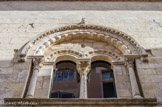 <center>Le Musée d'Art Sacré du Gard. </center> La baie centrale située à l'étage de la façade sur la rue Saint-Jacques a gardé son décor roman. Une large archivolte ornée de motifs en croisillon protège une frise de lourdes perles en forme d'olives qui s'appuie sur des colonnes à chapiteaux. A l'intérieur, sous un tympan autrefois peint et décoré d'un bacino hispano-moresque (coupelle aux motifs végétaux de lustre métallique), deux baies géminées cintrées, dont les gorges sont remplies de modillons profilés à l'antique irrégulièrement posés, sont réunies par une colonne cannelée surmontée d'un chapiteau.
Il faudrait situer la réalisation des chapiteaux de la Maison des Chevaliers, et donc de la façade, au cours de la dernière décennie du XIIe siècle. Le reste du décor confirme l'influence aixoise qui s'est exercée dans la Basse Vallée du Rhône à cette époque.