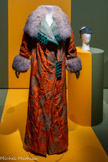 <center>Paul Poiret, la mode est une fête</center>Paul Poiret. Manteau du soir, vers 1910.Gros de Tours liseré à décor broché de fils doré et de lames argent, taffetas changeant, passementerie et métal argenté. Paris, musée des Arts décoratifs, dépôt UFAC, 1995. Don Marcel Piccioni.
Pour ce spectaculaire manteau, Paul Poiret a choisi une étoffe orientalisante d’essence historiciste particulièrement vive et précieuse évoquant les soieries Lyonnaises dites « bizarres » du XVIIIe siècle ; le jeu de contraste avec la doublure verte est aussi l’une des signatures stylistiques du couturier qui présenta ce modèle à la presse, assorti d'une capeline et d’une ombrelle japonaise, en juillet 1910, lors d’un défilé dans les jardins de sa maison de couture. <br>
Paul Poiret Coiffe 1914. Mousseline brodée de strass, fibre cellulosique et taffetas de soie. Paris, musée des Arts décoratifs.