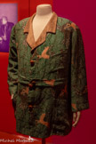 <center>Paul Poiret, la mode est une fête</center>Paul Poiret
Veste de travail ayant appartenu à Paul Poiret vers 1920
Toile de lin imprimée à la planche de bois d’après un dessin de l’Atelier Martine, crêpe de soie façonné et cuir tressé Paris, musée des Arts décoratifs, dépôt UFAC, 1995 Don Denise Boulet-Poiret. <br>
Celte veste de type Norfolk dont Paul Poiret possédait plusieurs exemplaires, est étroitement liée à son identité de créateur. Portée dans le cadre de son métier de couturier, de ses activités de peintre amateur ou même pour une séance photo, elle est d’une coupe toujours identique, boutonnée et ceinturée à la taille. Elle peut cependant présenter des variations ornementales : ici, le dessin de feuillages et de biches bondissantes imprimé par l'Atelier Martine renvoie à diverses références qui ont nourri sa créativité, en particulier l’iconographie des miniatures persanes ou celle des célèbres tableaux de « jungles » du peintre Henri Rousseau (1844-1910) dont il fut un grand admirateur.