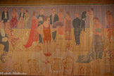 <center>Paul Poiret, la mode est une fête</center>Raoul Dufy
Tenture, La Présentation des mannequins chez Poiret
Livrée par l'artiste à Paul Poiret pour la péniche Orgues
1925
Toile de coton imprimée et peinte en couleurs rongeantes. Centre Pompidou, Paris
Musée national d'art moderne - Centre de création industrielle, achat, 1937
En dépôt au musée des Arts décoratifs de Paris depuis 1985
Raoul Dufy Bianchini Ferier
Cette tenture illustrant un défilé de modèles Poiret est la huitième d’un ensemble de quatorze toiles exécutées par Raoul Dufy, destinées à habiller les murs de la péniche Orgues, où a lieu chaque après-midi une présentation des créations de la maison de couture. Réalisée dans son atelier de Tournon avec le concours technique de la maison lyonnaise Bianchini Férier, elle est composée de trois lés assemblés et d’une bordure imprimée dans lesquels évoluent les personnages sans notion d’échelle. L’artiste applique ici sur des motifs préalablement dessinés le procédé des couleurs dites « rongeantes», qui s’incrustent dans la toile en se substituant à la teinte d’origine.