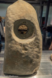 <center>CRAPAUDINE</center>Âge du Bronze récent (1600 à 1200 av.n.è.)
Pierre dure.
Cette pièce servait de pivot de porte.
Les concrétions marines peuvent venir d'une longue exposition sous-marine ou de son réemploi comme ancre.