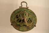 <center>Miroir à boîte orné d'une tête de satyre</center>Époque ptolémaïque, IVe - IIIe siècle av, J.-C.
Bronze, fonte pleine et décor appliqué
Genève, Fondation Gandur pour l'Art,