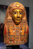 <center>Masque doré de momie</center>Époque ptolémaïque, 323-30 av. J.-C.
Égypte
Cartonnage doré (papyrus agglomérés, stuqués et peints) Rueil-Malmaison, musée d’Histoire locale, Mairie/Les Sites Patrimoniaux, Don M. et Mme Comte-Génin. <br> 
Ce masque était posé sur la tête d’un défunt momifié. Son visage doré évoque l’éclat du soleil.
A l’avant de la perruque sont figurées l’âme du défunt, sous forme d’un oiseau à tête humaine, et l’adoration du dieu des morts. Sur le front, symbole de renouveau, un scarabée ailé pousse le disque solaire.