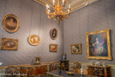 <center>Le cabinet de travail </center>C’est dans cette pièce qu’Edouard André puis Nélie Jacquemart organisaient leur vie quotidienne et recevaient leurs relations d’affaires. Curieusement, ce salon n’est pas aménagé à la façon austère d’un cabinet ministériel, mais présente au contraire un décor intime composé des objets qu’ils préféraient. On retrouve au mur une série de tableaux de grands maîtres français du XVIIIe siècle : Fragonard, Lagrénée, Coypel, Pater, Greuze. Une fresque de Tiepolo provenant d’un palais vénitien décore le plafond. Pour l’aménager, les époux André rassemblent des meubles tout aussi prestigieux : fauteuils estampillés Chevenat recouverts de tapisseries d’Aubusson, secrétaire en laque du Japon orné de bronze dorés attribués à B.V.R.B., commode Louis XV en bois de rose avec marqueterie en bois de violette attribué à l’ébéniste Joseph Baumhauer, bureau Louis XV estampillé par Jacques Dubois, l’ébéniste préféré du roi. <br> A gauche : Commode à deux tiroirs.
Joseph BAUMHAUER
Bois de violette, de rose et d’amarante sur bâti de chêne, marbre en onyx
Vers 1750. <br>Lustre
Italie ou France Bois doré
Début du XVIIIe siècle