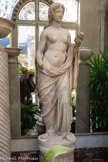 <center>Le jardin d'hiver</center>Statue de Flore ou Nymphe Art gréco-romain
Marbre IIe siècle. <br>
Le jardin d’hiver est caractéristique de l’art de recevoir qui se développe sous le règne de Napoléon III. Venue de Grande-Bretagne, cette innovation connaît un grand succès. Elle consiste à disposer, sous le couvert d’une verrière, des plantes en pots, le plus souvent exotiques. Cet espace végétal permet aux invités de venir se reposer un instant dans un cadre plus rafraîchissant que les étouffants salons voisins. Ce vestibule pavé de marbre, aux murs revêtus de miroirs, donne accès au très étonnant escalier à double révolution. Les sculptures qui le décorent en font une galerie d'antiques. Mais les plantes qui le garnissent rappellent que cette pièce a d'abord été un jardin d'hiver, inondé par la lumière que diffuse la verrière.