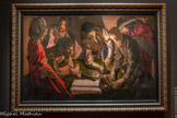 <center>Georges de La Tour Entre ombre et lumière</center>GEORGES DE LA TOUR (1593-1652)
L’argent versé.
Vers 1621-1634 Huile sur toile.
Galerie nationale Borys Voznytsky, Lviv, Ukraine. <br>
Rare œuvre datée - bien que l'inscription reste indéchiffrable -, l'Argent versé, redécouvert dons les années 1960, a remis en cause l'idée que La Tour n'aurait peint des nocturnes qu'à la fin de sa carrière. Dans un intérieur sombre, six personnages, saisis en frise sous un point de vue légèrement surplombant se livrent à une transaction. Le sujet reste énigmatique : collecte d'impôts, réquisition militaire ou tractation officielle, autant de scènes plausibles dans la Lorraine de l'époque. La précision des détails - notamment la nature morte composée par le registre, les pièces et h corbeille sur la table-, le contraste entre les costumes raffinés et la rudesse des gestes et l'usage dramatique du clair-obscur marquent une adhésion au caravagisme. La Tour captive en substituant à l'anecdote une ambiance tendue, animée par une sourde violence, une menace ou un soupçon.