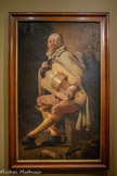 <center>Georges de La Tour Entre ombre et lumière</center>GEORGES DE LA TOUR (1593-1652)
Le Vielleur à la sacoche
Vers 1640 Huile sur toile
Musée Charles Friry, Remiremont. <br>
Georges de La Tour a peint au moins cinq versions de ce musicien ambulant, personnage familier des rues lorraines au XVIIe siècle. Des mentions dans les inventaires de l'époque de « joueurs de vielle» ou de « ménestriers» prouvent le goût des amateurs pour ces sujets. La Tour s'empare du thème avec un réalisme saisissant, loin des caricatures gravées par ses contemporains. Le clair-obscur dramatique et l'économie de moyens concentrent l'attention sur ce personnage solitaire et probablement aveugle. Le visage ridé, les cheveux en désordre, les vêtements modestes mais soignés du vieillard sont représentés avec précision. Ni misérabiliste ni idéalisé, ce portrait grandeur nature incarne une humanité discrète, à la fois digne et fragile, proche des figures populaires rencontrées chez les caravagesques.
La simplification des formes - comme l'absence des ouïes de l'instrument - annonce un dépouillement propre aux dernières années de La Tour.