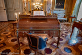 <center>Grand cabinet </center>Secrétaire à cylindre. 1784-1784. Secrétaire à cylindre en chêne, plaqué d'acajou moucheté. Les quatre pieds, légèrement courbes, se terminent en pattes de lion en bronze doré. L'angle extérieur des pieds est renforcé par deux baguettes parallèles en bronze doré, se terminant par une console en volute au niveau de la ceinture. Le secrétaire s'ouvre en façade par un long tiroir au centre et deux superposés sur les côtés. Ils sont cernés d'une baguette en bronze doré. Les poignées sont en forme de couronne de laurier et entourent une rosette. Une tablette peut être tirée de chaque côté du secrétaire. Le cylindre cache plusieurs compartiments. Il est surmonté de trois autres tiroirs. En s'ouvrant, le tiroir central libère une tablette ornée d'un maroquin vert. Une galerie ajourée en bronze doré surmonte le tout. Attribué à l'atelier de l'ébéniste Jean-Henri Riesener (1734-1806), ce secrétaire à cylindre a été commandé en 1784 par Marc-Antoine Thierry de Ville d'Avray, intendant général des Meubles de la Couronne, pour être envoyé dans son grand cabinet à l'hôtel du Garde-Meuble. En 1785, il meuble le cabinet intérieur du comte de Provence à Fontainebleau. <br> Fauteuil tournant. Henri Jacob.  1750-1799. Fauteuil en deux parties : d’une part un support en bois reposant sur quatre pieds fuselés et cannelés, accueillant d’autre part l’assise en bois et cuir, permettant à la partie supérieure de pivoter. L’assise, circulaire, est garnie de cuir noir. Les accotoirs à volutes rentrantes rejoignent le dossier mouluré, en chapeau de gendarme, également garni de cuir.