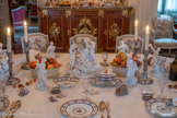 <center>La Salle à manger </center>Surtout : le Triomphe de Bacchus. biscuit porcelaine tendre.  Groupe en biscuit représentant Bacchus assis, uniquement couvert d'un tissu passant entre ses bras et sa jambe gauche. Le dieu tient une coupe à boire de la main droite. Autour de lui, deux bacchantes debout s'affairent : celle de gauche verse du vin depuis une amphore dans sa coupe tandis que l'autre s'apprête à le couronner de fleurs. A l'avant, aux pieds de Bacchus, deux putti jouent, les mains dans une corbeille de fruits. A l'arrière, un troisième putto tend une grappe de raisin à une panthère allongée qu'il enlace. Le socle imite un cadre naturel : troncs, cep de vigne et de larges rochers plats sur lequels sont posés pêle-mêle tambourin, cymbales, amphores, coupe à boire, flûte de Pan et masque grimaçant de théâtre, constituant les attributs de Bacchus.<br> A droite, groupe en biscuit représentant une bacchante debout jouant des cymbales, le pied gauche posé sur une amphore. A sa droite, un satyre nu, assis sur un rocher, souffle dans une trompe.