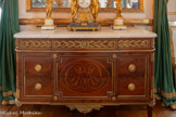 <center>Chambre d'apparat de Mme Thierry de Ville d'Avray.</center>Commode. Jean-Henri Riesener. Commode en acajou et bronze doré, reposant sur quatre pieds fuselés cannelés et couverte d'un plateau de marbre blanc. Elle se divise en trois travées, celle au centre étant plus large et recevant un décor incrusté de bois plus clair formant les initiales CML. Trois petits tiroirs s'ouvrent dans la ceinture. Le décor de bronze doré marque les extrémités des pieds et compartimente le corps de la commode. Sous la travée centrale, un culot feuillagé dépasse de la traverse, qui consiste en une baguette de bronze doré. Les angles antérieurs du corps de la commode sont arrondis et accueillent des cannelures rudentées en partie inférieure et des fleurons prolongeant les rudentures en partie basse, faisant face à des fleurons descendant de la partie supérieure des cannelures. La travée centrale est encadrée de baguettes de bronze doré, doublées d'une moulure et d'une frise de perles, formant un rectangle horizontal aux bords rentrés occupés par quatre roses. Le cartouche central met en valeur les initiales en bois clair. Les travées latérales sont plus fines et ne sont délimitées que par trois bordures, la quatrième étant cachée sous la travée centrale.