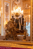 <center>Salon diplomatique</center>Pendule en bronze doré de style rocaille, constituée de rinceaux abritant un faune allongé et deux putti, reposant sur des pieds. Le faune barbu occupe la partie centrale, faisant pendant à un grand rinceau cachant le fût de la pendule. Le cadran est entouré de chutes de pampres et de deux putti ailés tournés vers le faune. Seul élément régulier et circulaire de cet ensemble, le cadran est néanmoins doté d'aiguilles reprenant le style végétal rocaille de la pendule. 1850-1899