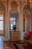 <center>Salon diplomatique</center>Au trumeau de la glace, des ancres de marine entrelacées avec des dauphins. Bas d'armoire. 1860-1860. bas d’armoire à hauteur d’appui en marqueterie et bronze doré, couvert d’un dessus de marbre vert. Ils reposent sur une plinthe aux angles abattus marqués par un dé de raccordement à rosace en bronze. Les montants sont garnis de bronzes en entrelacs et chutes de fleurs et surmontés d’un motif de console d’acanthe en agrafe. La façade est divisée en trois panneaux faisant vantaux. Les deux panneaux latéraux reçoivent un ornement de bronze doré à décor de grappes de fruits, le panneau central reçoit un décor de marqueterie de fleur figurant un grand bouquet au naturel dans un vase. La ceinture abrite un tiroir richement orné d’un culot d’acanthe et de rinceaux. Le plateau de marbre vert est souligné par une fris d’oves en bronze doré.