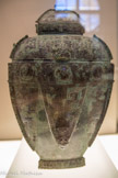 <center>Musée Cernuschi. </center> Vase Fanglei pour les liquides. Bronze. Époque de Anyang (vers 1300 - vers 1050 av. J.-C.). Dynastie des Shang (vers 1550 - vers 1050 av. J.-C. Elle possède trois anses ; deux d’entre elles, placées à hauteur de l’épaule, permettent de soulever le récipient. Une troisième, en bas de la panse, est ornée d’une tête de bovin. À hauteur de l’épaule, un masque de bélier en fort relief décore la face principale du récipient. Des motifs en très léger relief couvrent le reste de la pièce.