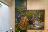 <center></center>Le Déjeuner sur l'herbe, 1865-1866 par Claude Monet. Le tableau, laissé en gage puis racheté, est incomplet, depuis que l'artiste n'en a laissé subsister, par une découpe en 1884, que la partie centrale, le reste étant endommagé par l'humidité. Une autre découpe fut opérée après 1920, à droite du tableau. Le tableau entier, donc complet, montrait douze personnes. Dans l'élément subsistant, les protagonistes sont vêtus de vêtements à la mode parisienne de l'époque. Ils pique-niquent près de la clairière d'une forêt. Tout le monde est rassemblé autour d'une nappe blanche posée au sol, où se trouvent mets, fruits, gâteaux et vin. L'ambiance dans cet espace naturel est principalement créée par le jeu de la lumière et de l'ombre, favorisé par les trouées d'un feuillage au-dessus des personnages. Monet a représenté l'artiste Gustave Courbet assis à gauche dans la composition, près de Mme Monet, Camille Doncieux, première épouse de l'artiste. Il est accompagné par Frédéric Bazille, debout près d'une femme remettant ses cheveux en place. On entrevoit les robes longues de deux femmes, à droite et à gauche.  En 1987, par dation en paiement de droits de succession, le fragment central du Déjeuner sur l’herbe de Claude Monet est venu rejoindre au musée d’Orsay la partie gauche de cette grande composition, offerte par Georges Wildenstein en 1967.