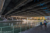 <center>Parc de la Villette </center> « De Passage » est une installation artistique lauréate du Budget Participatif 2014 de la ville de Paris, inscrite dans le projet global intitulé « Reconquête Urbaine », qui matérialise le lien qui unit Paris et Pantin. Cette œuvre artistique lumineuse ouvre une 3ème rive, la voie du haut. Celle-ci est une invitation à lever la tête et à se laisser guider par une constellation de signes lumineux qui accompagnent et racontent la vie du lieu à ceux qui traversent cet espace.
La voûte s'illumine en fonction du passage des piétons, cyclistes, péniches et dessine in situ l'orchestration de tous ces flux métropolitains traversant ce passage.
En l'absence de passage, l'œuvre impulse ses propres mouvements, un clapotis lumineux qui s'écoule à la surface de la voûte.
Les passants peuvent aussi devenir chef d'orchestre de cet orgue lumineux au niveau de deux zones sensibles marquées au sol par une étoile, de chaque côté des rives du canal. Quelques mouvements de bras impulsant des risées de lumière, passant d'une rive à l'autre.