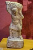 <center>Figurine</center> Le personnage porte sur ses épaules un sac de blé. Céramique. Époque romaine.