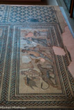 <center>Mosaïque</center>Dionysos en cortège accueille les convives, alors que le tapis géométrique autour indique l'emplacement des banquettes.