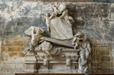 <center>Eglise de St Trophime</center>Chapelle des rois. L'ange de la résurrection soulève le couvercle du tombeau, d'où semble se relever le prélat sculpté d'après nature. À droite, assise au pied du tombeau, une mère allaitant un enfant et abritant un autre sous son manteau, figure l'image de la Charité. Au-dessus sont groupés trois anges déployant l'écusson du prélat : laurier de sinople, au chef d'azur chargé de trois étoiles d'or, et l'épitaphe de l'archevêque.