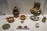 Au fond, Oenochoé subgéométrique. Le Marduel, St Bonnet (Gard) Troisième quart du Ve siècle av. J.-C. et Urne non tournée avec couvercle. Roque de Viou, St Dionisy (Gard) Première moitié du IVe siècle av. J.-C.. Au milieu, Trousse de toilette en fer (spatule, pince à épiler, scalptorium). Roque de Viou, St Dionisy (Gard) Dernier quart du IVe siècle, Tasse à anse à décor peint Roque de Viou, St Dionisy (Gard). Troisième quart du IVe siècle av. J.-C., Coupe à anse à décor peint Mauressip. St Côme et Maruéjols (Gard) - Première moitié IVe siècle av. J.-C. et Petite cruche massaliète en céramique claire peinte. Espeyran. Saint-Gilles (Gard). IVe s. av. J.-C. Devant, Disque en bronze à rebord perlé. La Jouffe, Montmirat (Gard). VIe - Ve s. av. J.-C., 
Fragments de vases attiques à figures rouges. Mauressip, St Côme et Maruéjols (Gard). Première moitié IVe siècle av. J.-C. et Fibule à pied replié sur l'arc. Roque de Viou, St Dionisy (Gard) Deuxième moitié du IVe siècle av. J.-C.