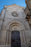 <center>Saint-Laurent-la-Vernède.</center> Telle qu’elle est aujourd’hui, cette église est de style romano-byzantin et sa façade ressemble à la façade de toutes les églises que le diocèse de Nîmes doit à Mr Bègue, architecte d’Uzès. Le portail de l'église est carré, surmonté d’un plein cintre avec tympan portant une croix grecque entourée de feuillages sculptés. Deux archivoltes à gros boudins sans sculpture viennent reposer sur l’entablement des quatre colonnes très gracieuses et au-dessus des archivoltes il y a trois arcs surhaussés dont les retombées sont prolongées par des verticales. Les arcs sont simples et sans moulures.