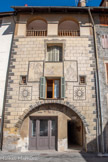 Saint-Etienne-de-Tinée. <br> Maison FABRI (1656). Construite par Fabrice FABRI, descendant d’une grande famille stéphanoise, cette maison est décorée au début du 18ème siècle, probablement après le départ d’une petite communauté carmélites, installée depuis le milieu du 17ème siècle. 
C’est un bel exemple rare de façade baroque, avec consoles de masques grimaçants et armoiries des FABRI dominant un fronton curviligne, dans la montagne niçoise.