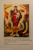 <center>Les 5 statues de Notre-Dame de la Garde.</center>Ex-voto avec la Vierge à l'ostensoir. Autour d'une statue de la Vierge, tenant de la main droite un ostensoir et sur le bras gauche l'Enfant Jésus, on peut voir 2 femmes agenouillées en prière, 2 navires, 2 falaises surmontée la première d'un mur et l'autre d'un fort gardé par un soldat. De nombreux drapeaux sont hissés sur les navires et sur les fortifications.
On peut reconnaitre le pavillon du royaume de Sardaigne bleu au canton de Savoie sur le navire à 2 mâts et voiles carrées, un pavillon turco-barbaresque rouge frappé de 3 croissants d'or sur le navire à la voile latine, un pavillon espagnol jaune à 2 bandes rouges sur la muraille, un drapeau à queue d'hirondelle de l'ordre de Malte (ou du Danemark) sur le fort, un drapeau rouge, blanc, rouge et des flammes blanches et bleues.