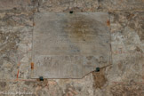<center>Les travées des cryptes. </center>Cet enfeu a été construit afin de recevoir la sépulture de Hugues de Glazinis, auteur de l'achèvement de l'église abbatiale dans la première moitié du XIIIe siècle. Le texte de son épitaphe peut se traduire ainsi : « Hugues, sacriste, que recouvre cette pierre étroite / se réjouit avec les saints d'être le compa¬gnon de Michel, dans les deux / Ici-bas, fleur et parure de tous les moines / vénérant les saints, à bon droit il est enseveli dans ce temple / qu’il a construit dès le début presque en entier à partir des fondations / Ses membres y furent déposés le huitième jour de novembre / Si l'on ajoute mil à deux fois cent que l'on fait suivre de cinquante / on indique l’année à laquelle il a été établi au-dessus des astres ».
Au bas du texte figure un décor : au centre, accostée du soleil et de la lune, une croix se dresse entre deux candélabres ; à gauche est représentée la silhouette schématisée de l'église achevée, tandis qu’à droite, devant un autel, un prêtre est en posture d'oraison. Cette composition est évocatrice de la fonction du défunt et de son rôle de bâtisseur.