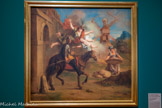 <center>Don Quichotte conduit par la Folie sort de chez lui pour se faire chevalier errant</center>Charles-Antoine Coypel.
Carton de tapisserie de la tenture de L’Histoire de Don Quichotte Paris, France, vers 1716. Huile sur toile.
Musée national du château de Compïègne, dépôt du musée du Louvre. <br>
Comme les 27 autres de la série, cette peinture est un modèle de tapisserie commandé par la manufacture des Gobelins. Elle a donc été énormément diffusée au 18e siècle, par la tapisserie comme par la gravure. Le peintre synthétise le début du roman : la folie, représentée sous les traits d’une femme ailée, coiffée d’un plat à barbe, fait voir géants et princesse à don Quichotte, là où il n’y a en réalité que moulins et paysanne. Mais surtout, elle est la force motrice qui le pousse à partir à l’aventure. Les efforts de ses amis pour le ramener à la maison et à la raison n’y pourront rien !