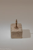 <center>Toute Petite Figurine</center>1937-1939
Plâtre
Fondation Giacometti
Lorsqu'il reprend son travail d'après modèle à la fin des années 1930, Giacometti est confronté à un problème qu'il a déjà rencontré dans sa jeunesse : l'échelle de ce qu'il voit ne correspond jamais à celle réelle des objets. L'artiste constate que s'il s'éloigne, pour en avoir une vision d'ensemble, leur taille diminue inévitablement à cause de la distance. Ainsi, quand il essaie de restituer le plus fidèlement possible les figures telles qu'il les voit, leur dimension se réduit « malgré lui ». Le socle devient alors un outil fondamental pour les rendre plus visibles.
C’est aussi cet élément qui permet de révéler le vide entourant la figurine tout en lui donnant une monumentalité, malgré sa très petite taille.