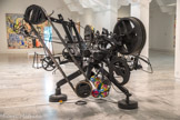 <center></center>Jean TINGUELY
I925, Fribourg (Suisse) 1991 Berne (Suisse)
Rotozaza I
1967
Métal bois, moteurs, transformateurs et ballons
Inv. 2007.2.42
Transfert de collection de l’état,. attribution au (mac] musée d'art contemporain de Marseille en 2008. Œuvre restaurée en 2013 avec le concourt du ministère de la Culture, Paris.
La formation de Jean Tinguely se portage entre la fréquentation irrégulière des Beaux-Arts de Bâle et l'apprentissage de la décoration de magasins. À Paris; en 1953,9 réalise des reliefs animés dont le mécanisme est caractéristique des machines à dessiner qu’il produira plus tard. Il est le créateur d'un monde de bruit et de jeu de bricolage et d’ombrea Construites en partie à l’aide d’objets de récupération ses mécaniques; délibérément imparfaites; refusent le culte de l’objet neuf, produit d’une société de consommation En 1960, Tinguely intègre le groupe des Nouveaux Réalistes. À partir de 1963, il peint ses machines en noir, les privant ainsi de leur caractère d’objets trouvés.