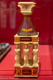 <center>Bouteille ornée des cariatides de l' Erechthéion.</center>Vers 1980, Grèce. Verre, plastique. Mucem, Marseille, dépôt du Muséum national d’histoire naturelle (collection d’ethnologie d’Europe), Paris..