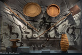 <center>Accrochage consacré à l’Algérie dans la « salle d’Afrique » du musée d’Ethnographie du Trocadéro, à Paris, vers 1900</center>1900-1934, Paris, France
Reproduction d'une photographie de Louis Lanièpce.
Musée du quai Branly - Jacques Chirac, Pari.s.
Dans cet accrochage de l'un des musées ayant précédé le Mucem, des outils donnés par le Gouvernement général d'Algérie sont disposés en éventail, évoquant les mises en scène de trophées de guerre. Une sculpture antiquisante évoque la « mission civilisatrice » qui serait celle de la France dans les colonies, renforçant le message de la propagande impériale.<br>
Fourche dite ferka
19e siècle (avant 1891), Algérie ou Tunisie Bois d’olivier.
Pelle
19e siècle (avant 1891), Algérie ou Tunisie. Bois.
