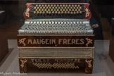 <center>Accordéon</center>Maugein Frères
1935-1939
Tulle, Corrèze, France
Ivoirine, carton, Bakélite, métal, cuir, nacre, papier. <br>
Les facteurs d’instruments de musique utilisent des matériaux précieux, souvent protégés, pour obtenir la meilleure sonorité qui soit. Pour les accordéons, instruments populaires par excellence, on a, dès le début du 20e siècle, utilisé des matériaux composites, comme la Bakélite ou l’ivoirine, pour remplacer la nacre ou l’ivoire.