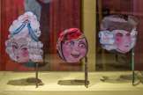 <center>Accessoires de fête</center>1900-1950 Paris, France
Bois, papier, carton, gouache
Décorés d'un visage peint, ces tambourins évoquent des masques « face à main ».
Ils sont parfois munis d'une crécelle, instrument fréquemment utilisé dans les pratiques carnavalesques. Les visages fardés évoquent l'univers du théâtre. Ces accessoires ludiques et festifs proviennent d'un fonds de boutique parisienne.