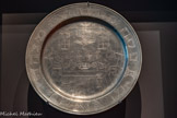 <center>Plat de seder.</center>1850-1900 Alsace, France Étain gravé
Ce plat témoigne du rituel du Seder : on y voit une famille réunie pour célébrer, au moment de la fête de Pessa’h, la commémoration de la fuite d’Égypte du peuple d’Israël. Ce type de plat est utilisé pour présenter les aliments spécifiques consommés lors de cette fête, chacun doté d’une valeur symbolique.