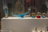 <center></center>Bouteille souvenir de pèlerinage 
Établissements Blanchard 1888
Lourdes, France
Verre moulé et peint, matière plastique. <br> Cendrier souvenir
20e siècle
Venise, Italie
Verre soufflé et coloré. <br> Boules à neige
20e - début du 21e siècle France, Italie et Autriche Plastique, résine, verre, polystyrène, eau