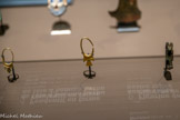 <center>Les objets funéraires de Carthage</center>Boucles d'oreilles en forme de croix ansée
VIIe-VIe siècle av. J.-C.
Or. <br> Amulette au représentant le dieu et appuyer contre un pilier percé.
Faïence.