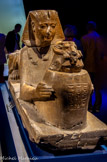 <center>Statue de Ramsès II en sphinx faisant offrande d’une vasque à tête de bélier.</center>La puissance absolue et la dévotion religieuse de Ramsès sont matérialisées par ce sphinx mi-homme mi-lion. L’image des lions, symboles de puissance physique tant hier qu’aujourd’hui, étaient étroitement liés à la royauté. Ici, Ramsès offre une vasque d’eau sacrée à Amon- Rê, roi des dieux. Ce sphinx assurait la garde dans le grand temple d’Amon-Rê à Karnak.