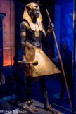 Statue en bois du gardien du Ka du roi, portant la coiffe Némès.
Les yeux au regard perçant du gardien sont faits d’obsidienne volcanique. Ses sandales et sur son front sont en bronze.
Bois, gesso, résine noire, feuille d'or, bronze, calcite blanche et obsidienne (yeux)