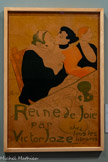 <center>Musée Toulouse-Lautrec</center>Henri de Toulouse-Lautrec
Reine de Joie
1892
Lithographie au pinceau et au crachis avec trame report, en quatre couleurs (pierre de trait en vert olive, pierres de couleurs en jaune, rouge et noir)
Albi, musée Toulouse-Lautrec (inv. A.4)
Donation de la Comtesse de Toulouse-Lautrec et famille, 1922
En 1892, Toulouse-Lautrec réalise une affiche pour promouvoir Reine de Joie de Victor Joze, dont la couverture est signée Pierre Bonnard. Le roman relate les amours entre le baron de Rozenfeld et la demi-mondaine Hélène Roland, et condamne la dépravation morale des riches tout en décrivant le monde des courtisanes. Reposant sur une diagonale inspirée des estampes japonaises, la composition met en scène les personnages attablés. Le texte, tracé par l’artiste, est remarquablement bien intégré à l’ensemble. Pourtant bien accueillie, cette affiche provoque un scandale : le banquier Alphonse de Rothschild voit dans le personnage créé par Joze une caricature de lui-même et tente de faire interdire l’affiche.